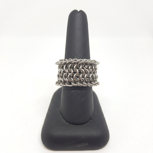 Wide stainless steel 4-in-1 weave chainmaille ring on a black display stand against a white background